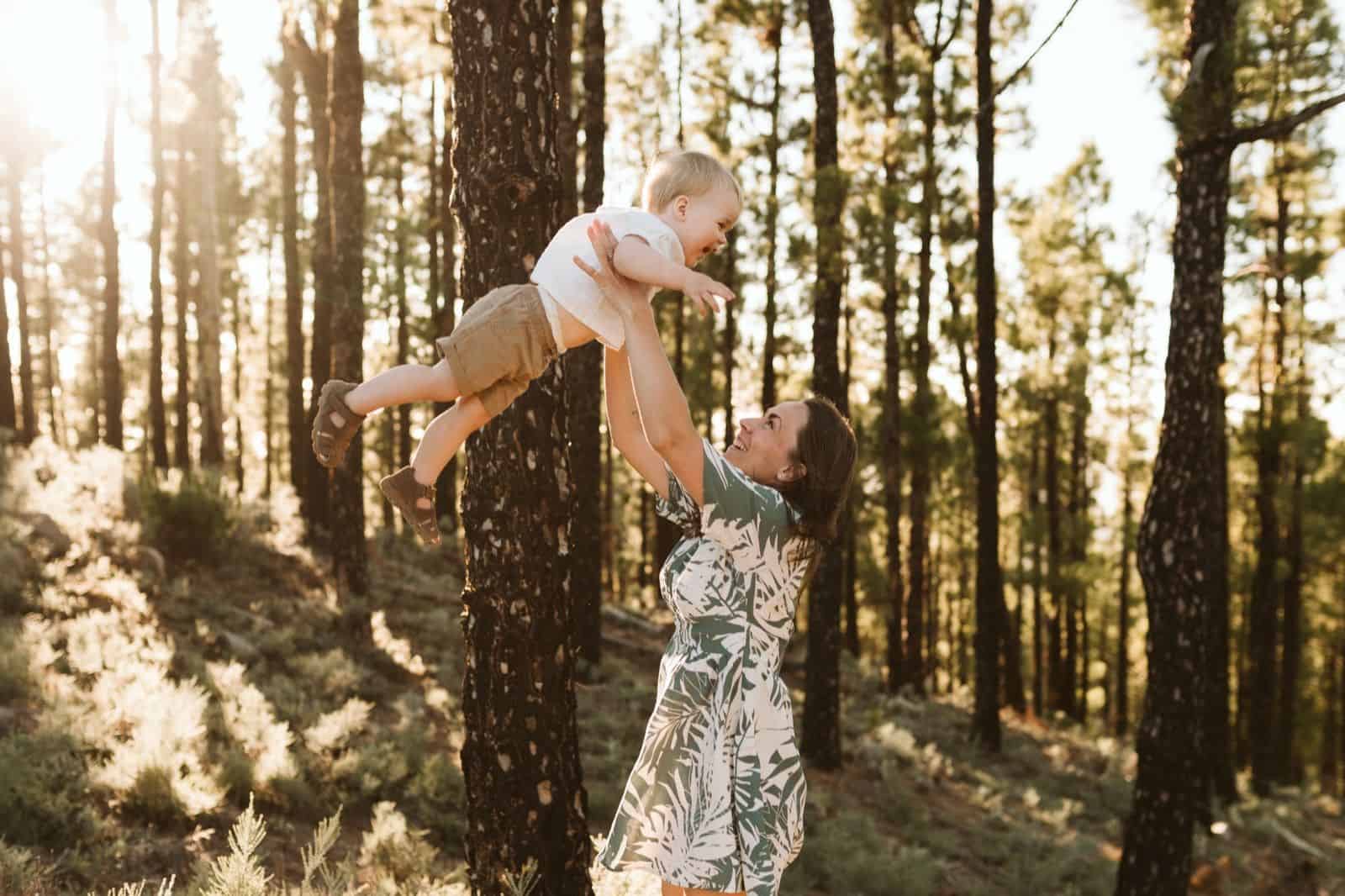Madre levantando a su hijo por los aires, jugando y haciéndole reír