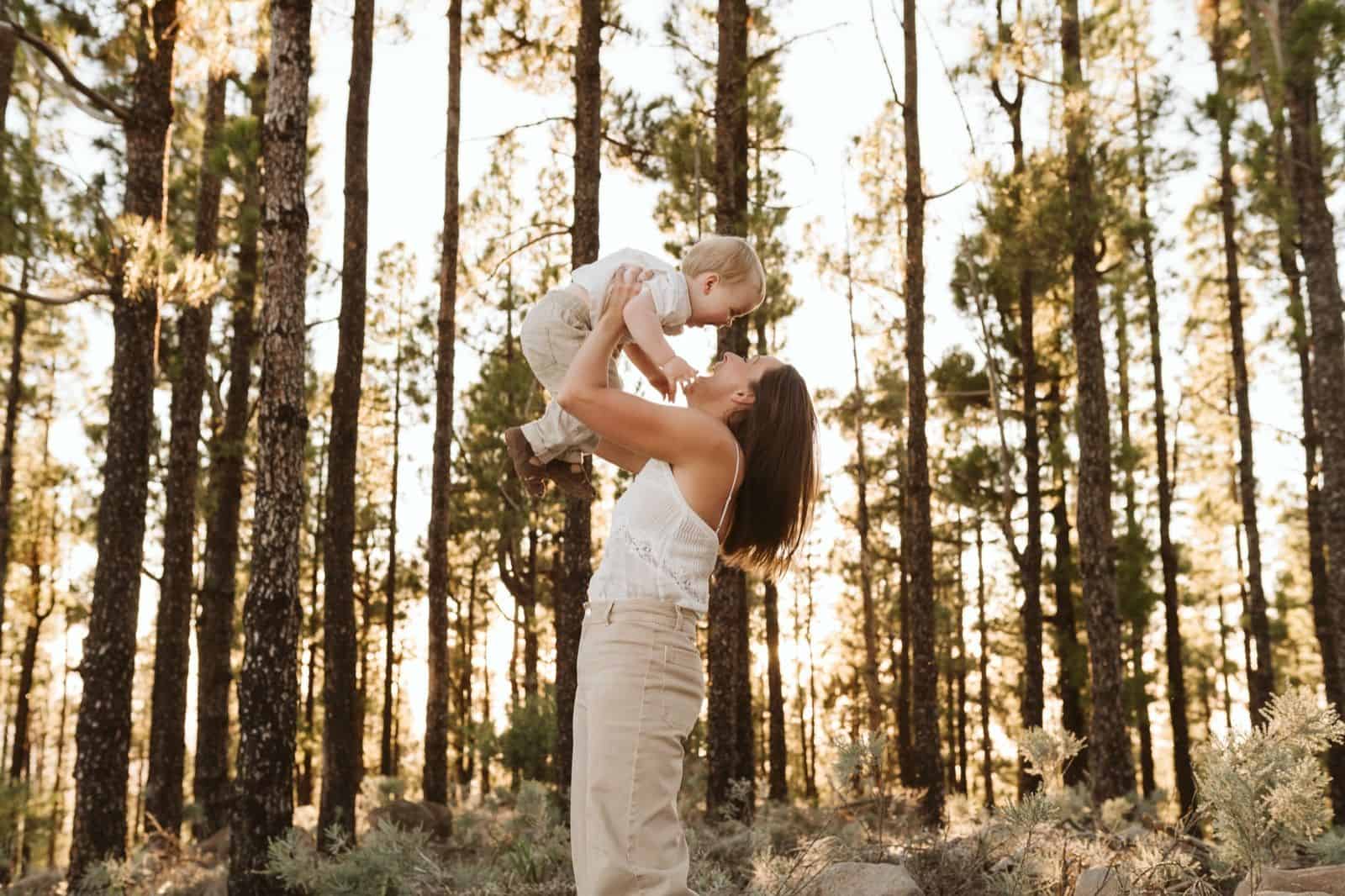 Madre levantando a su hijo por los aires, jugando y haciéndole reír