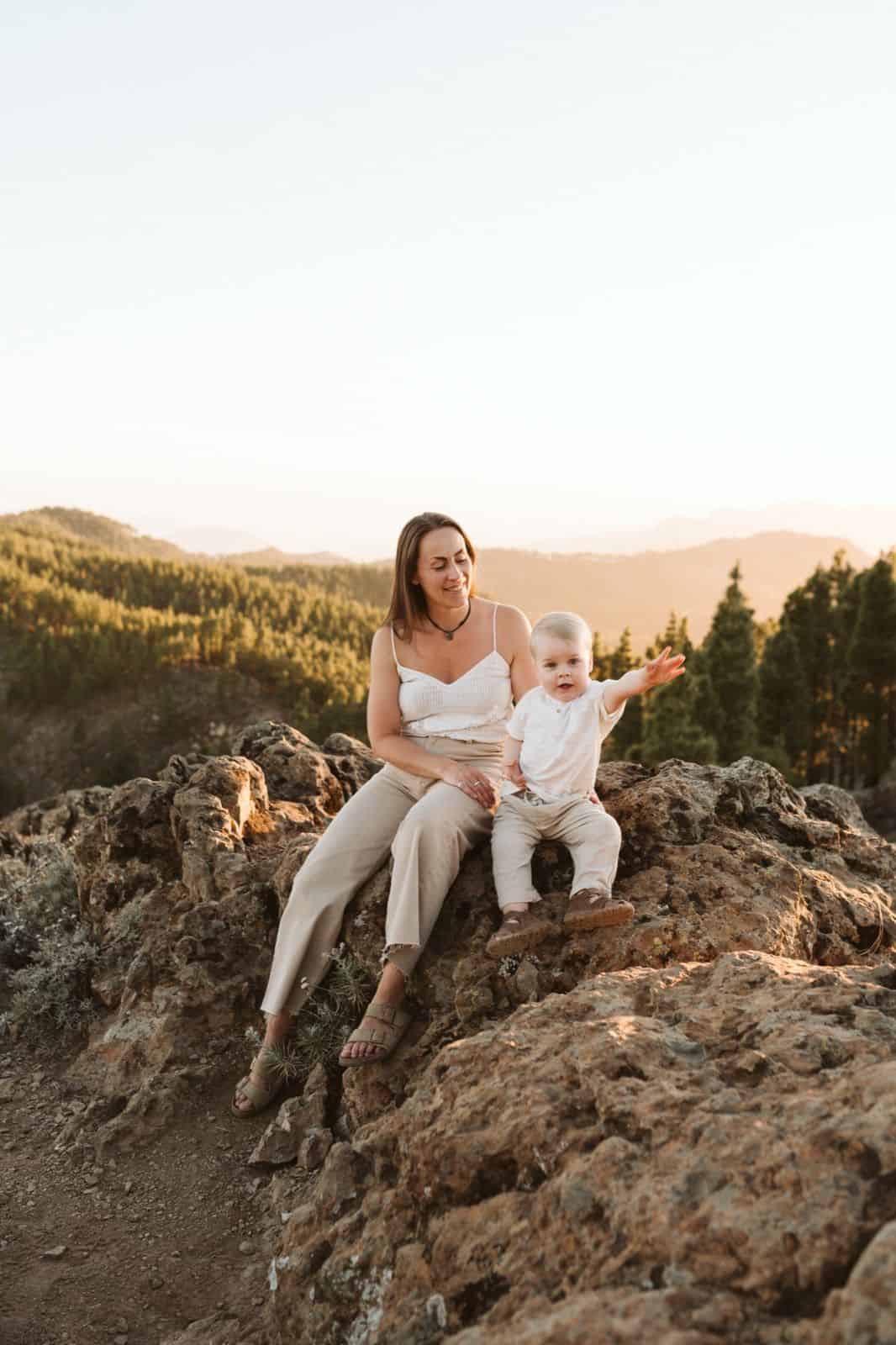 Madre e hijo sentados sonriendo en las montañas de Gran Canaria con un pinar de fondo