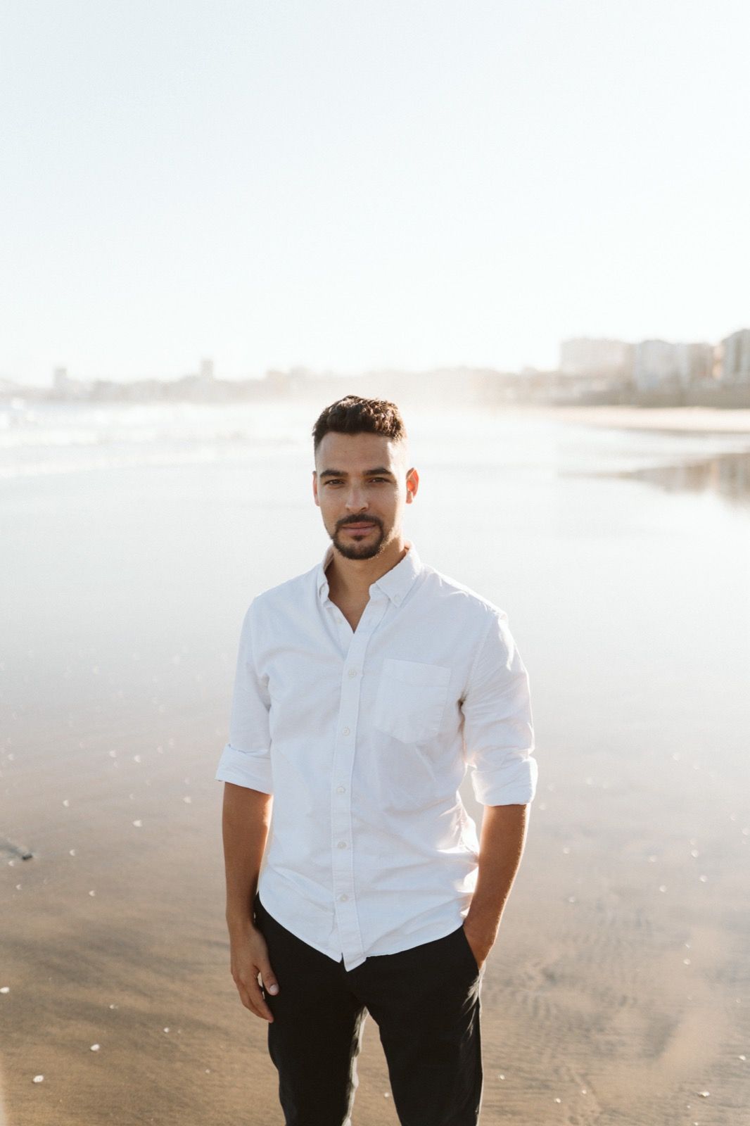 Hombre posando a la cámara sonriendo en la orilla de la Playa de Las Canteras en Gran Canaria durante las horas de marea baja. Fotografía realizada por el fotógrafo de familias en Gran Canaria Héctor Cardeñosa.