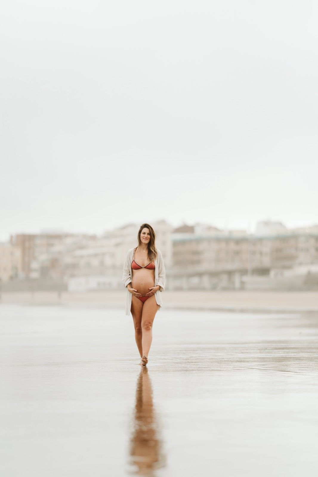 Sesión de fotos de embarazo en Las Canteras con la madre posando frente al océano Atlántico