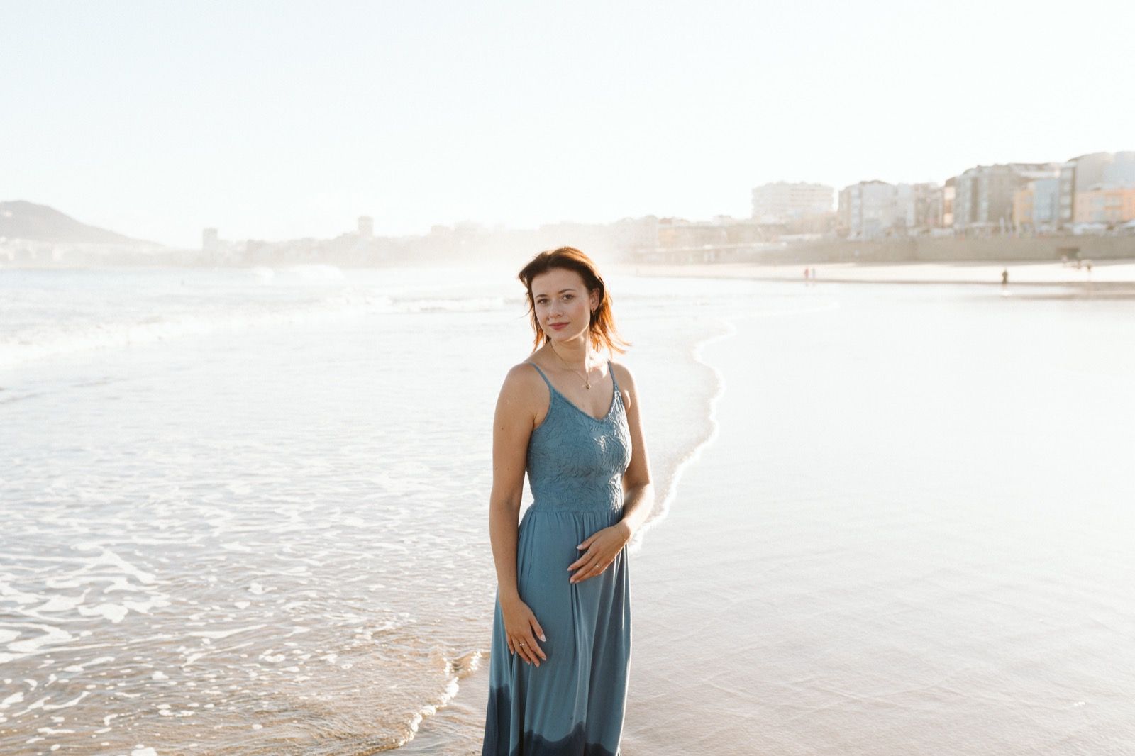 Mujer posando a la cámara sonriendo en la orilla de la Playa de Las Canteras en Gran Canaria durante las horas de marea baja. Fotografía realizada por el fotógrafo de familias en Gran Canaria Héctor Cardeñosa.