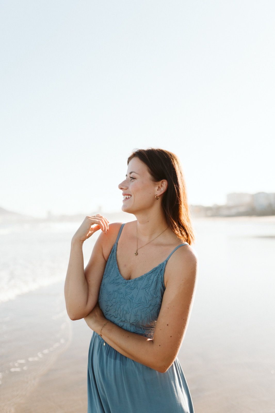 Mujer posando a la cámara sonriendo en la orilla de la Playa de Las Canteras en Gran Canaria durante las horas de marea baja. Fotografía realizada por el fotógrafo de familias en Gran Canaria Héctor Cardeñosa.
