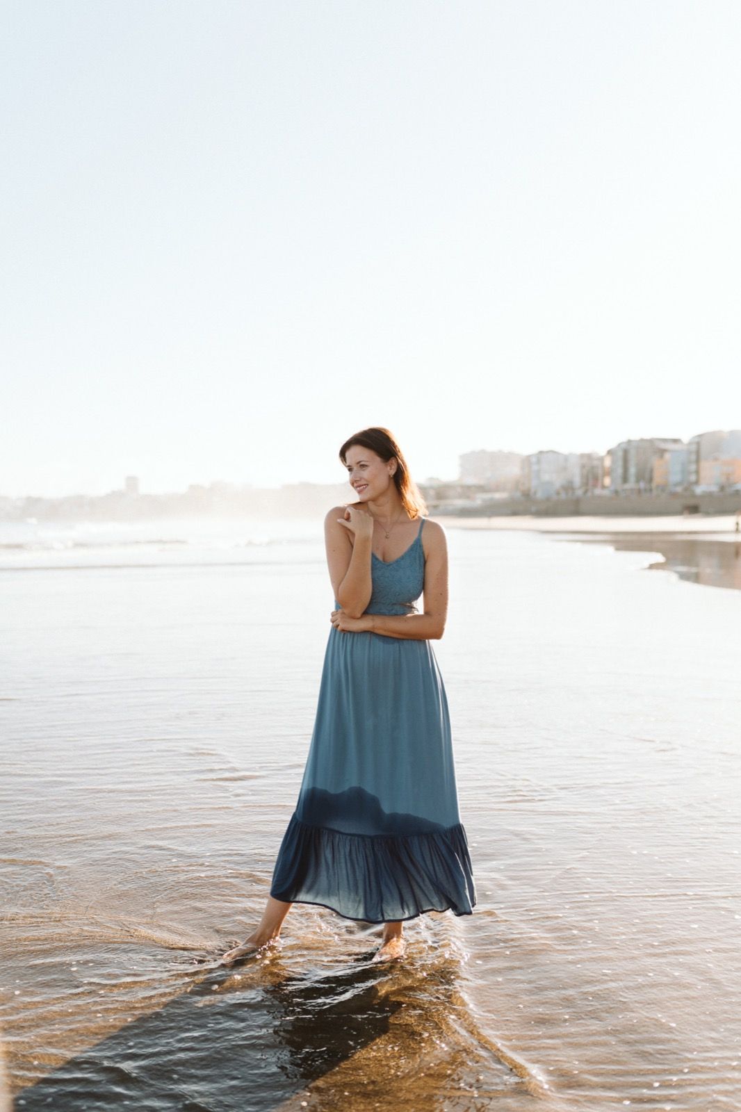 Mujer posando a la cámara sonriendo en la orilla de la Playa de Las Canteras en Gran Canaria durante las horas de marea baja. Fotografía realizada por el fotógrafo de familias en Gran Canaria Héctor Cardeñosa.