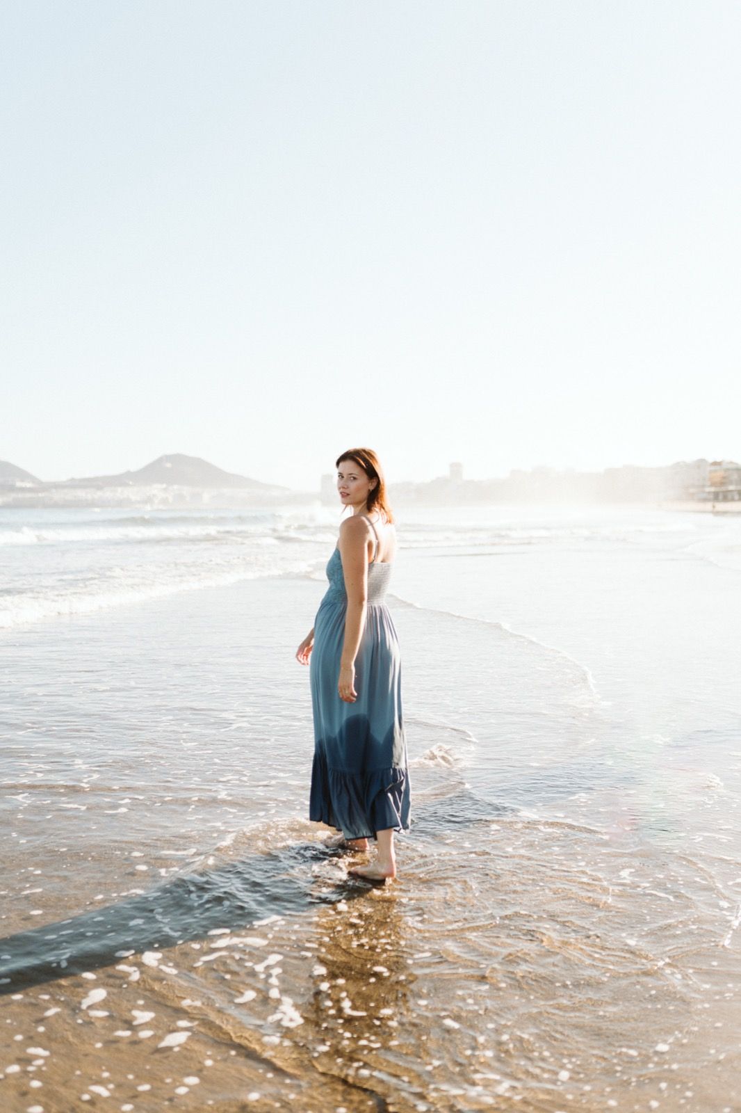 Mujer posando a la cámara sonriendo en la orilla de la Playa de Las Canteras en Gran Canaria durante las horas de marea baja. Fotografía realizada por el fotógrafo de familias en Gran Canaria Héctor Cardeñosa.