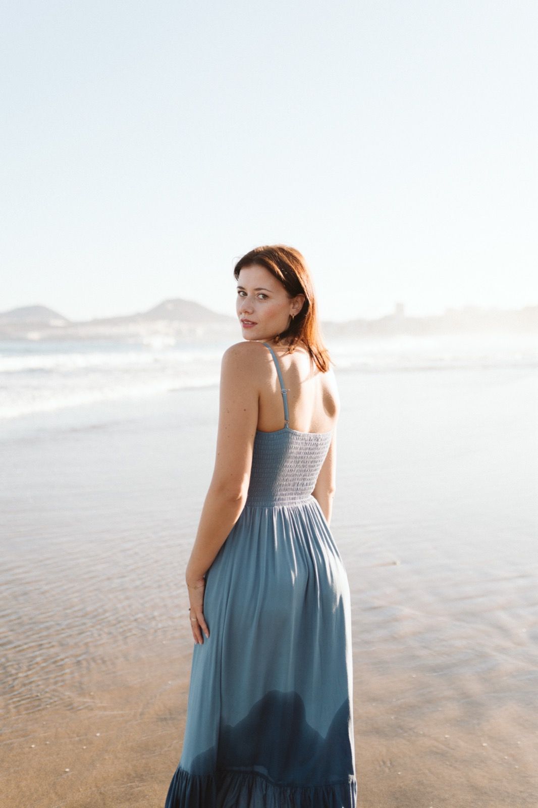Mujer posando a la cámara sonriendo en la orilla de la Playa de Las Canteras en Gran Canaria durante las horas de marea baja. Fotografía realizada por el fotógrafo de familias en Gran Canaria Héctor Cardeñosa.