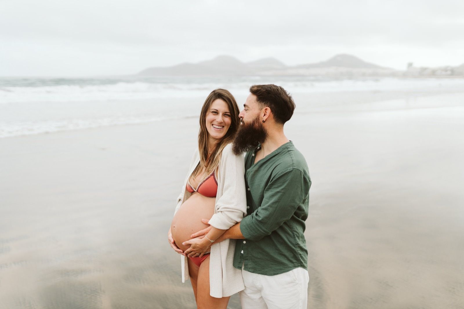 Pareja disfrutando de una sesión de fotos de embarazo en la playa de Las Canteras, Gran Canaria