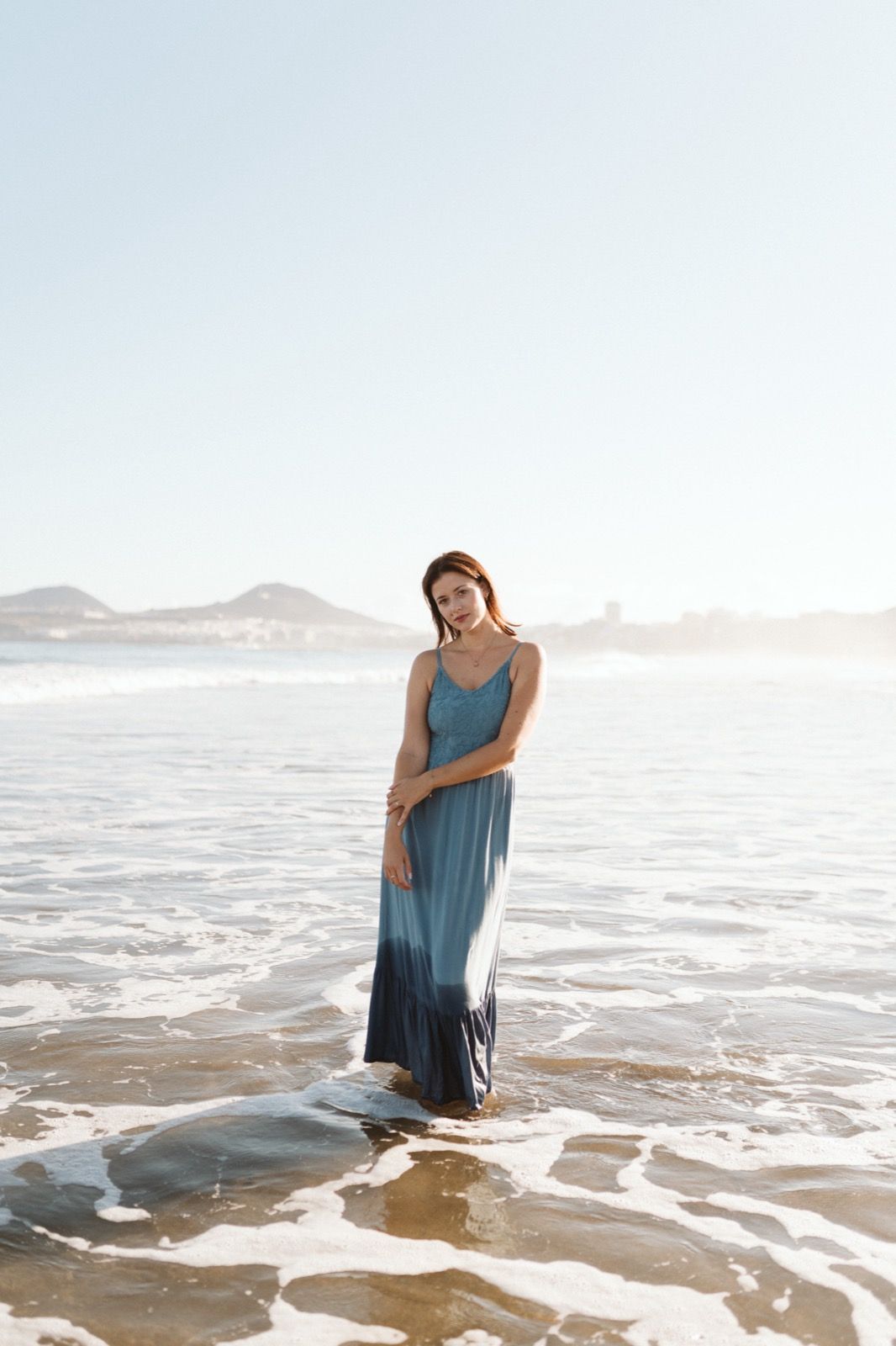 Mujer posando a la cámara sonriendo en la orilla de la Playa de Las Canteras en Gran Canaria durante las horas de marea baja. Fotografía realizada por el fotógrafo de familias en Gran Canaria Héctor Cardeñosa.
