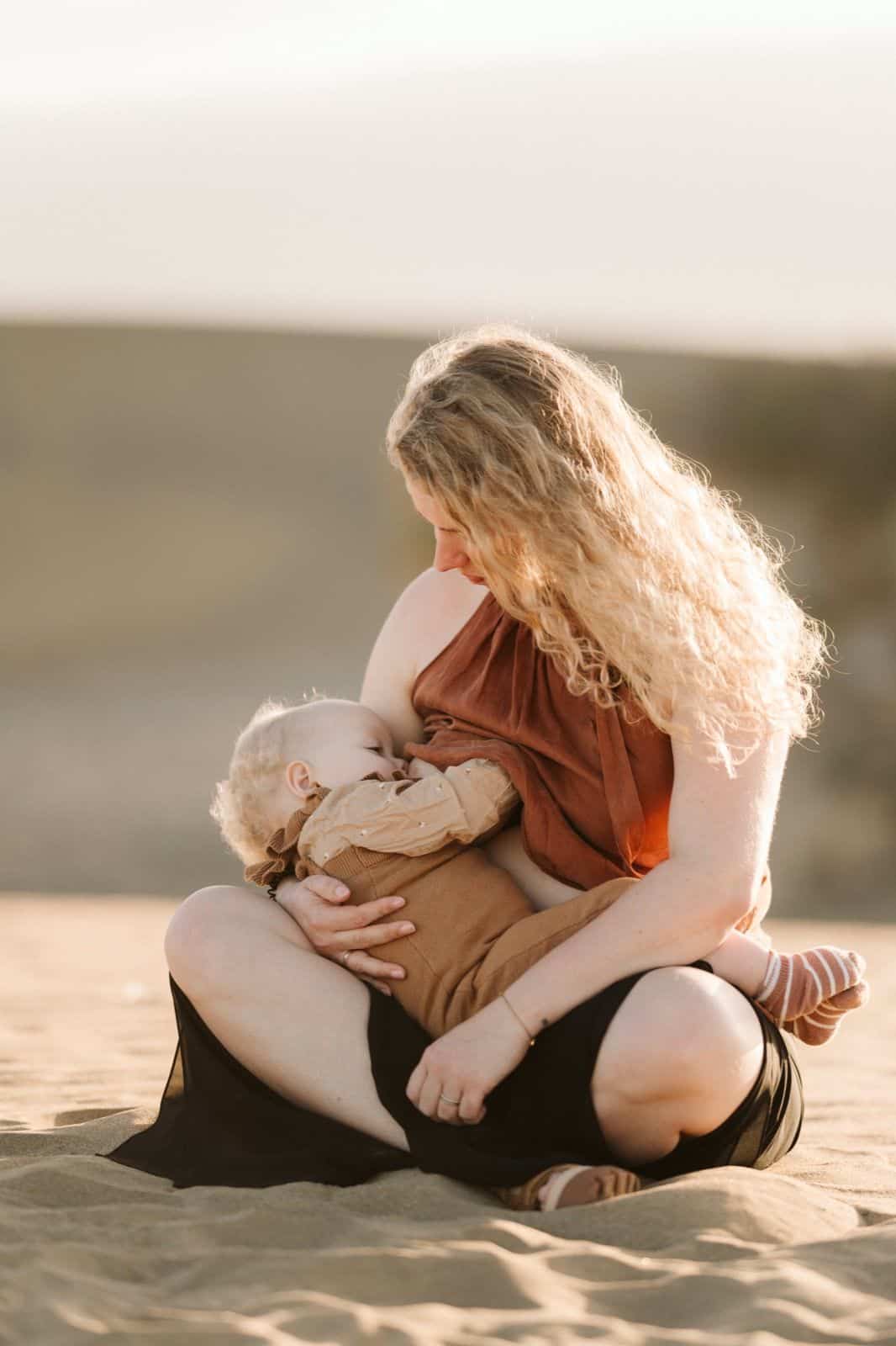 Mamá dandole el pecho a su bebé en un descanso de la sesión de fotos en las Dunas de Maspalomas en Gran Canaria
