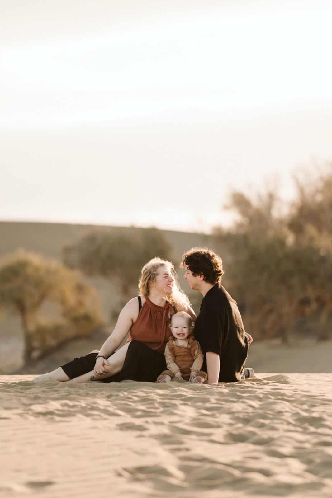 Pareja con su bebé disfrutando de una atardecer en las Dunas de Maspalomas en Gran Canaria