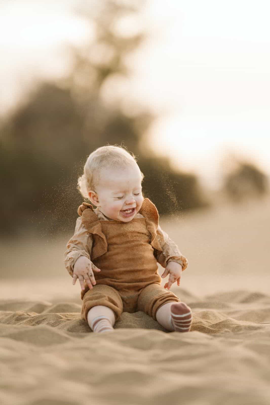 Bebé riendo mientras juega en la arena durante una sesión de fotos en las dunas de Maspalomas, Gran Canaria